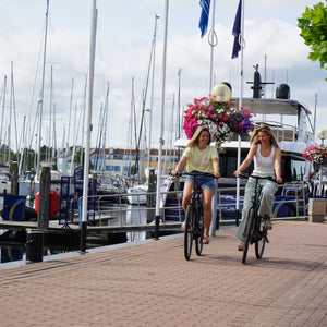 2 meisjes fietsen bij de haven op een gehuurde fiets van Wave and Wheels