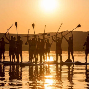 groep mensen tijdens ondergaande zon op een sup