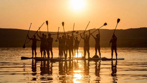 groep mensen tijdens ondergaande zon op een sup